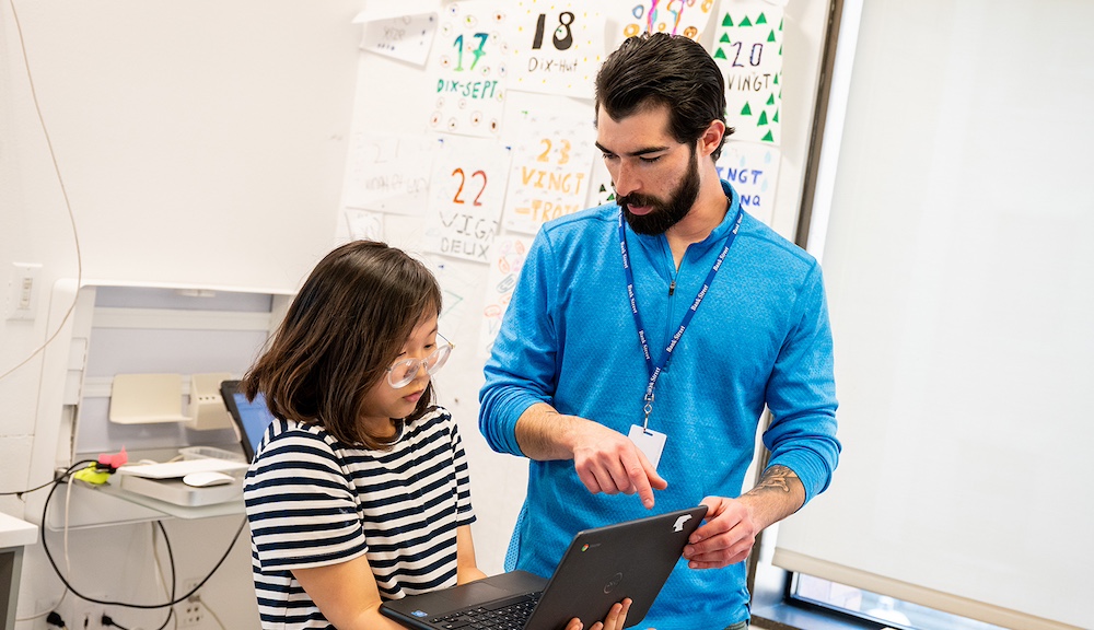 A teacher works with a student on a virtual learning assignment.