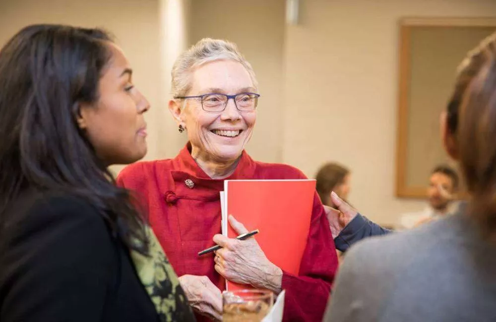 Dean Cecelia Traugh smiles in conversation with two teachers.